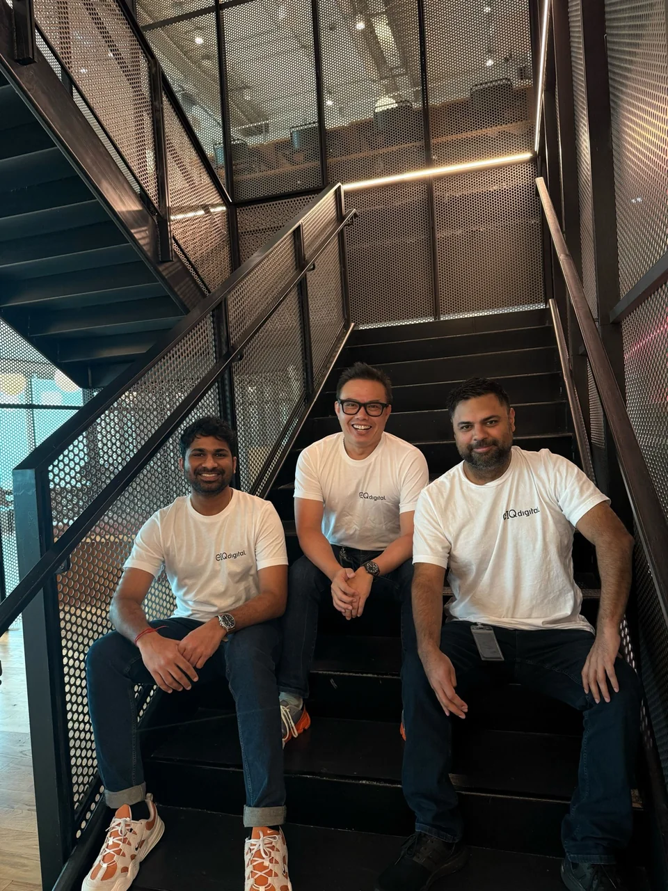 Dave and two colleagues in EIQdigital shirts sitting on steps.