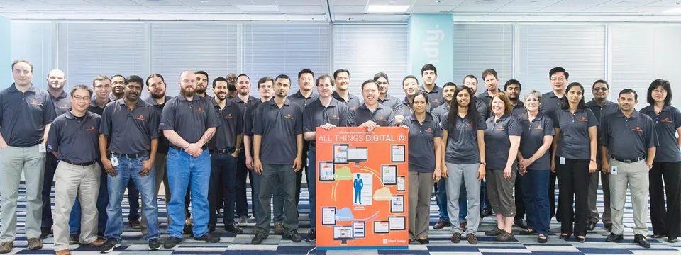 A team group photo with an All Things Digital poster and Direct Energy branding.