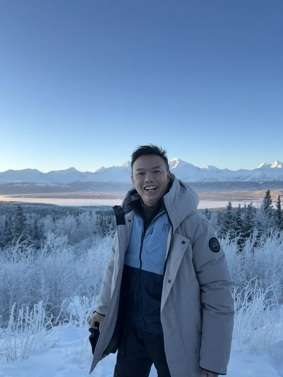 Dave in a winter coat with snowy mountains behind him.