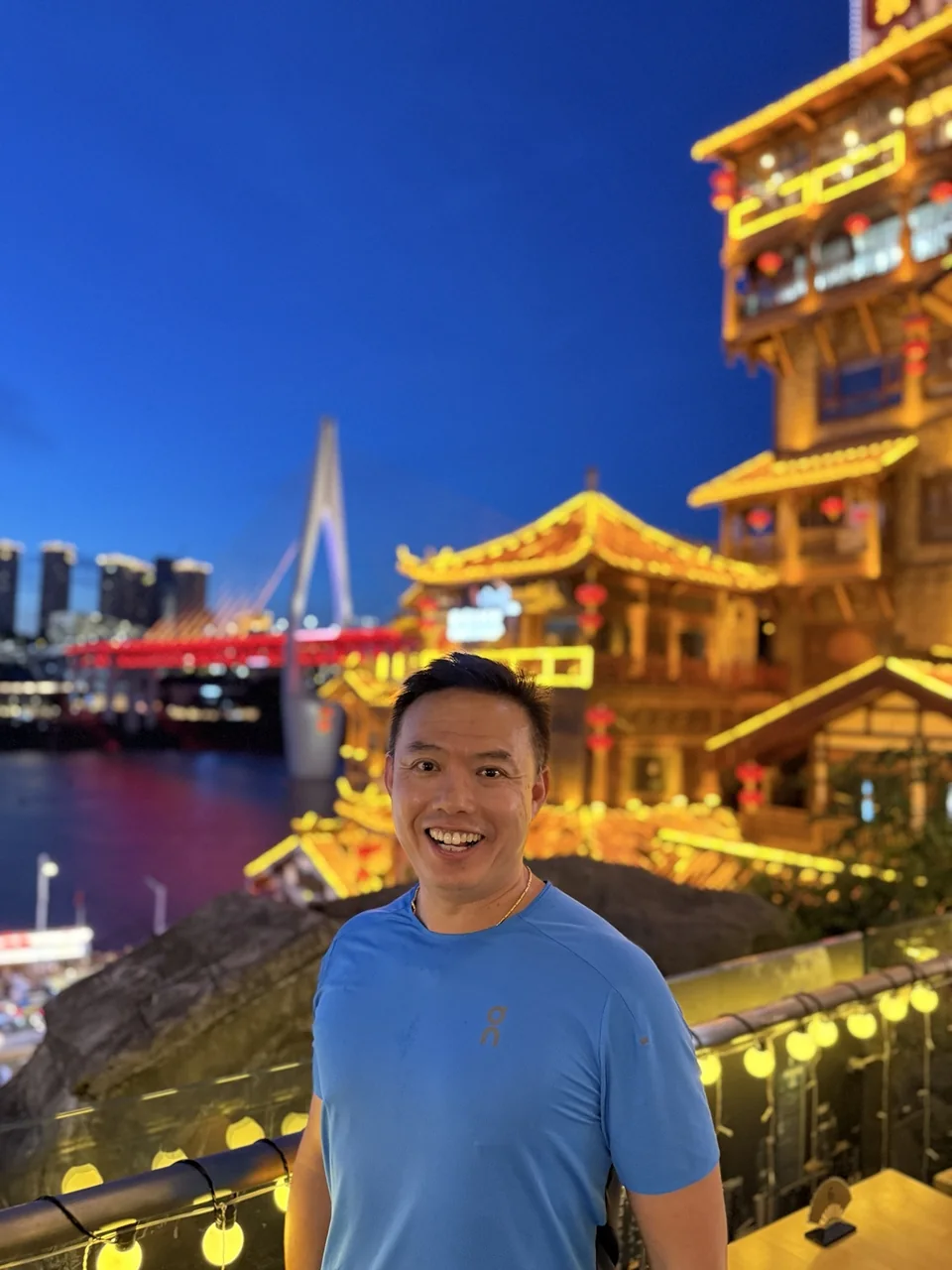 Dave smiling in a blue shirt with illuminated buildings behind him.